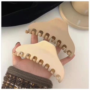 Handheld view of large matte hair claws in cream and light coffee colors for thick hair
