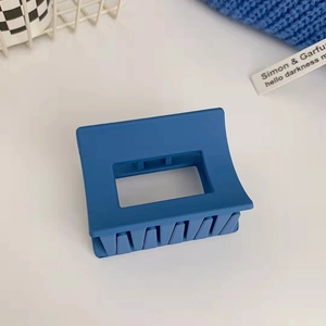 Primo piano di una pinza per capelli rettangolare blu Klein opaco su sfondo bianco e blu