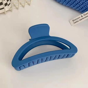 Dettaglio della molletta per capelli blu opaco con design traforato su sfondo bianco