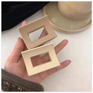 Close-up of matte rectangular hollow hair claws in beige and cream coffee tones