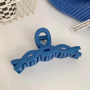 Dettaglio della pinza per capelli blu Klein opaca con struttura geometrica su fondo bianco
