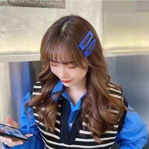 Vue détaillée d'une pince à cheveux géométrique bleu mat portée sur le côté par un modèle