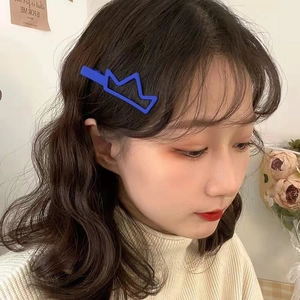 Gros plan d'une pince à cheveux couronne bleue mate portée comme accessoire élégant