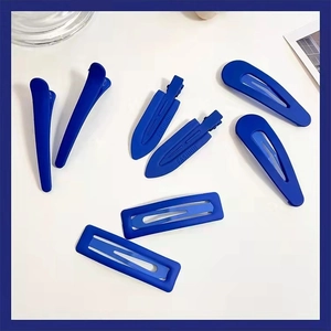 Vue à plat de diverses pinces à cheveux bleu Klein mat avec gravure sur fond blanc