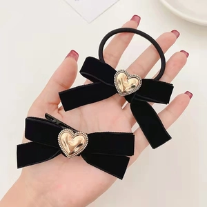 Détail d'un ensemble chouchou et barrette en velours noir avec des cœurs dorés