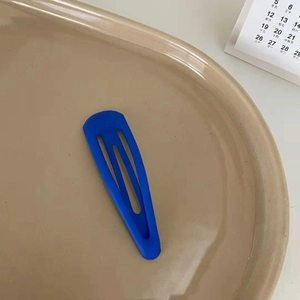 Pince à cheveux bleue mate Klein sur un plateau en céramique kaki pour un style quotidien