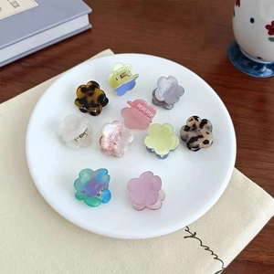 Nahaufnahme von 10 Mini-Blumen-Haarklammern aus Acryl in verschiedenen Farben auf einem Teller