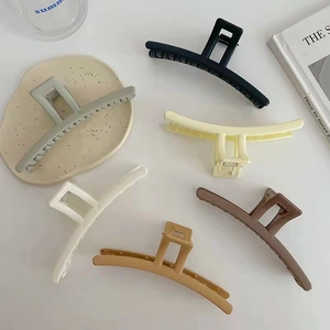 Set of six matte long hair claw clips in assorted neutral colors on a white tabletop