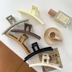 Detail view of large matte hair claws in six soft colors arranged with lifestyle props