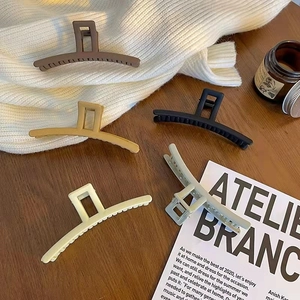 Detailed view of five matte rectangular hair claws in autumn colors on a cozy table