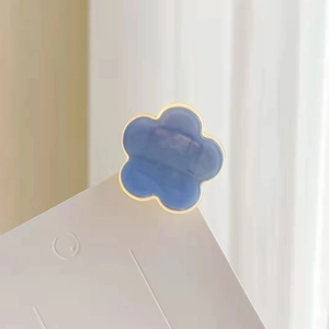Nahaufnahme einer kleinen blauen Haarklammer in Blütenform auf einer weißen Karte