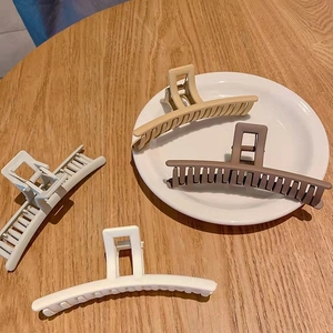 Close-up of four matte square hair claws in beige and brown colors on a wooden surface