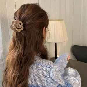 Molletta per capelli a fiore opaco color moka su un'acconciatura a metà raccolta