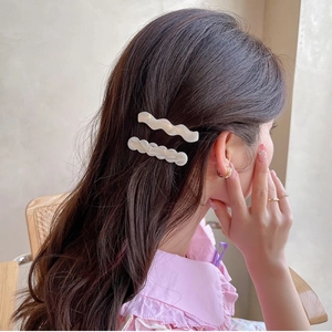 Gros plan de barrettes à cheveux ondulées blanc cassé nacré portées par un mannequin