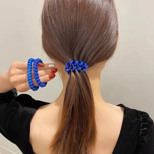 Élastique spirale bleu mat porté au poignet et sur une queue de cheval stylée