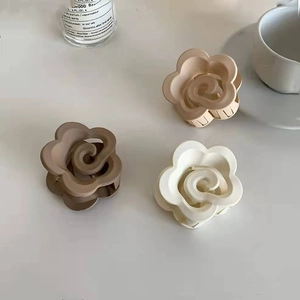 Dettaglio di tre mollette per capelli a fiore opaco in avorio, moka e tè al latte