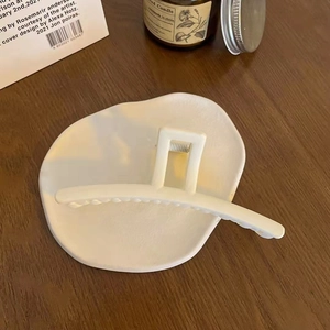 Detailed macro shot of a matte white hair claw clip placed on a ceramic tray