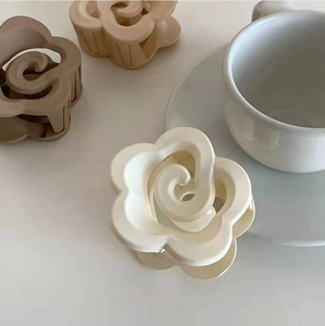 Eleganti mollette per capelli a fiore opaco nei toni crema e marrone su un tavolo