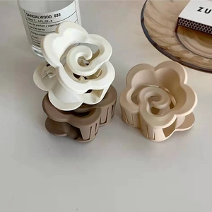 Dettaglio di tre mollette per capelli a fiori opachi in bianco beige e marrone