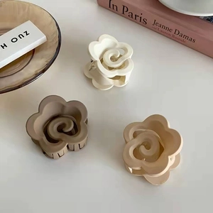 Dettaglio di tre mollette a fiore opaco nei colori crema, moka e tè al latte