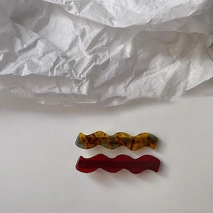 Vue détaillée des pinces à cheveux ondulées en acétate écaille et rouge bordeaux