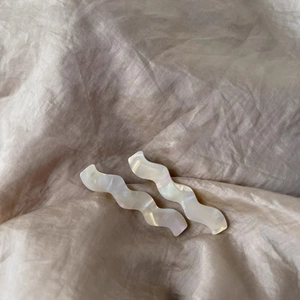 Détail de pinces à cheveux ondulées nacrées sur un fond de tissu en soie lisse
