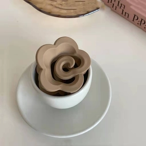 Dettaglio della molletta per capelli a fiore marrone opaco in una tazza di porcellana