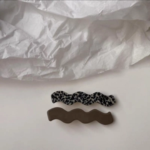 Vue détaillée des pinces à cheveux ondulées avec motif vache et finition marron foncé