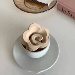 Dettaglio dell'elegante molletta per capelli a fiore beige con finitura opaca