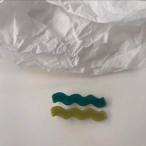 Vue détaillée de pinces à cheveux ondulées en résine dans les tons vert foncé et herbe