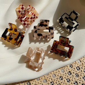Detailed set of acetate checkered and tortoiseshell patterned hair claws on white fabric
