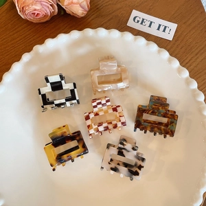 Set of six mini acetate hair claws with checkered and tortoiseshell patterns in a ceramic dish