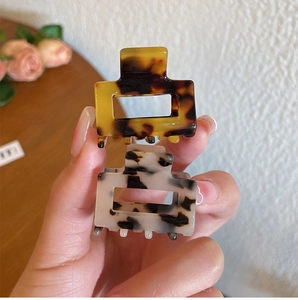 Close-up of leopard print acetate hair clips held in hand with retro floral background