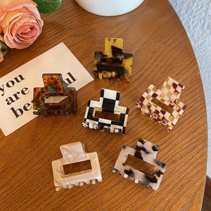Set of six mini leopard and checkerboard acetate hair claws on a warm wooden table