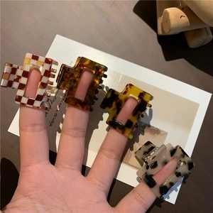 Detail showing four acetate hollow rectangular hair claws in various leopard and checkered patterns