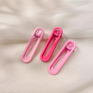 Detailed macro view of three matte pastel pink and purple hair clips on soft tulle
