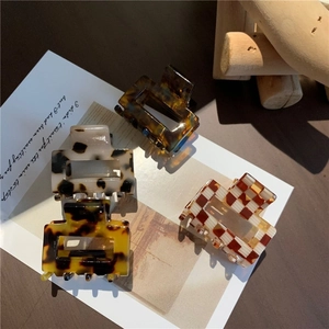Close-up of four checkered and leopard acetate square hair claws on a card