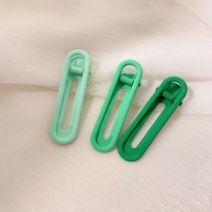 Macro detail of three matte green gradient oval hair clips on soft tulle fabric background