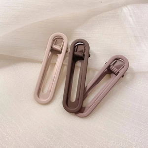 Close-up of three matte candy-colored hair clips in beige, brown and pink on fabric
