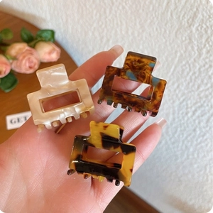 Macro detail of three acetate square claw clips in marble and tortoiseshell patterns