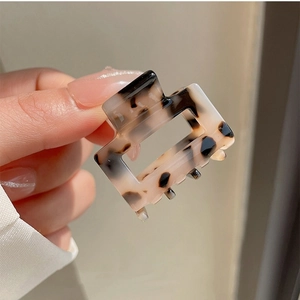 Close-up of a small square cream tortoiseshell claw clip with dark brown leopard spots