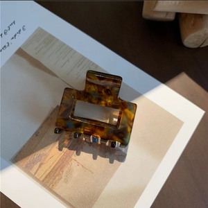 Close-up of tortoise shell square acetate hair claw clip on vintage magazine paper