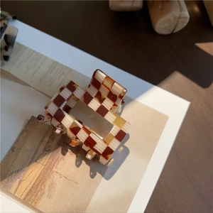 Close-up of brown and white checkered acetate hair claw clip with cutout design
