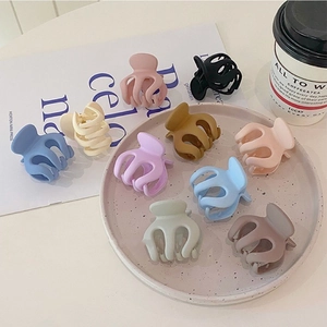 Flat lay of colorful matte hair claw clips in Morandi colors on a stylish pink tray