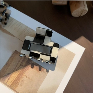 Detail of a minimalist black and white checkerboard hair claw clip on a stylish card