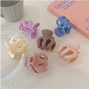 Set of six colorful matte hair claw clips for high ponytail styling on a decorative tray