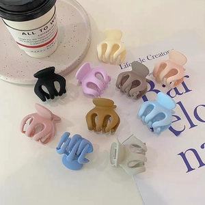 Detailed view of small matte hair clips in various colors spread on a white background
