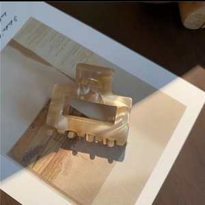 Close-up of rectangular acetate hair claw clip with beige marble texture on card