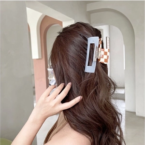 Detail of checkered pattern acetate hair claw clip styled on long wavy hair