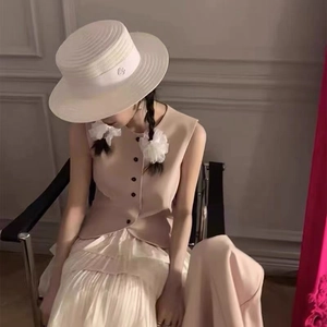 Femme élégante en haut sans manches rose clair et jupe plissée à plusieurs niveaux crème